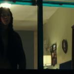 Lex Scott Davis as Nya, peers from the window of her tenement apartment.
